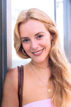 Portrait of a blonde woman with a smiling, Focus on her facial features and natural beauty, captured outdoors with soft lighting and an urban background.