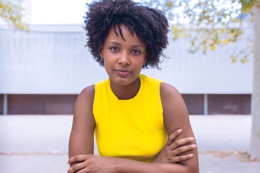 Portrait of black woman with a smiling, thoughtful expression. Focus on her facial features and natural beauty, captured outdoors with soft lighting and an urban background.