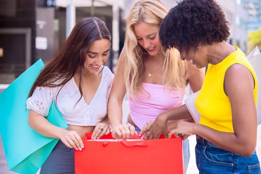 A group of three women happily inspecting their shopping bags on a city street. Cheerful and vibrant atmosphere showcasing friendship, shopping, and shared joy in an urban setting.
