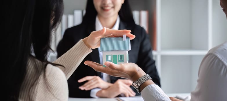 A couple finalizes a real estate sales contract with an agent, representing a new home purchase and investment opportunity.