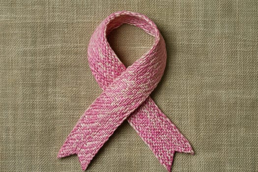 This image features a handcrafted pink ribbon made of woven fabric, symbolizing support and awareness. Perfect for campaigns and creative projects.
