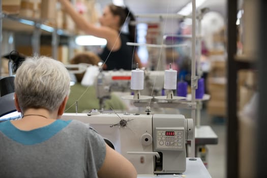 Woman sewing in workshop sitting in rearview