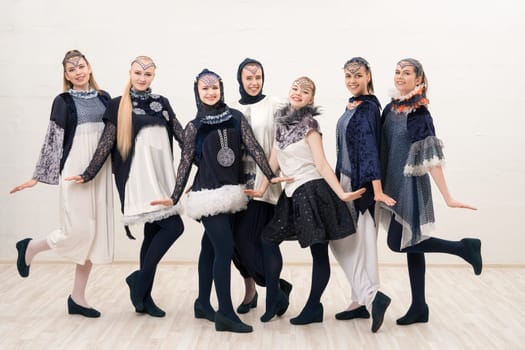 Group of beautiful girls in artistic design costumes isolated full-length view on white