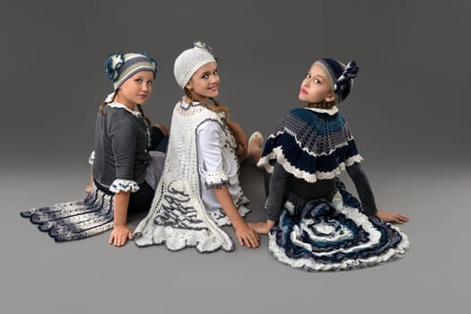 Pretty girls wearing fashion white and blue costumes and hats sitting on the floor rearview
