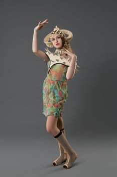 Girl wearing fashion colorful dress and hat view against gray wall
