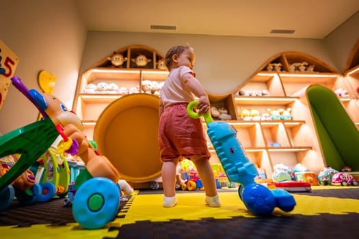 Child exploring with a toy vacuum cleaner in a vibrant and interactive playroom designed for creativity and motor skill development
