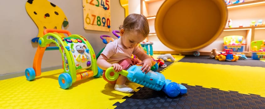 Little child using a toy vacuum cleaner for pretend play in a vibrant playroom with interactive learning tools