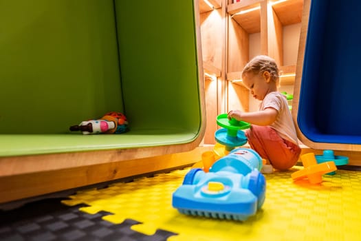 Young child enjoying educational playtime with colorful activity toys in a safe and modern playroom