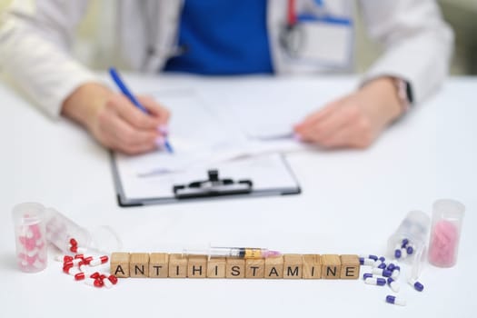 A healthcare professional carefully composes a prescription for antihistamines, showcasing various pills displayed