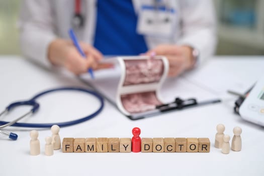 A family doctor reviews key medical info using wooden figures and a stethoscope during the consultation