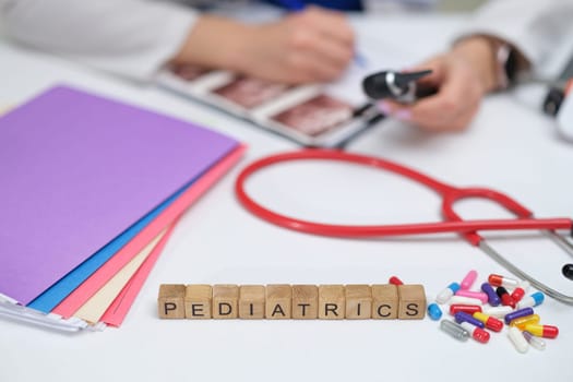 A pediatricians workspace that prominently features various documents, a stethoscope, and colorful medications