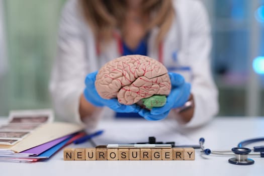 A trained medical professional presents a brain model, emphasizing the importance of neurosurgery education