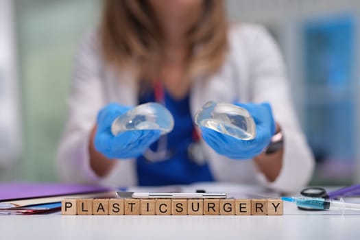 A plastic surgeon holds silicone implants in a clinical setting, emphasizing cosmetic surgery options.