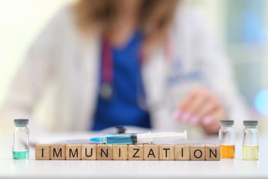 A healthcare worker organizes vaccine vials, spelling out immunization with building blocks to raise awareness