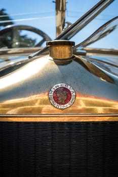 Lisbon, Portugal - Sep 29, 2024: Close-up of Minerva logo grille badge with Roman goddess profile and radiator cap in selective focus on sunny day. Shiny hood cover of Belgian pre-war luxury car, Minerva, Belgium, 1920s.