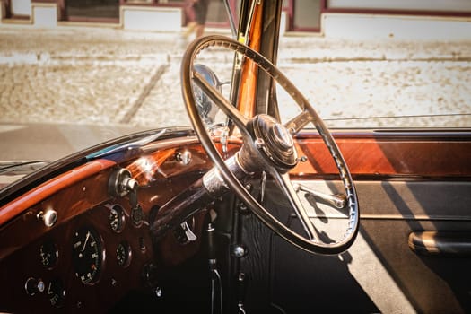 Lisbon, Portugal - Sep 29, 2024: Close-up and selective focus on vintage luxury 1937 Rolls-Royce Phantom III interior. Steering wheel and dashboard in wood, leather and chrome lit by sunlight.