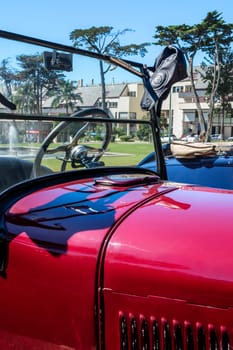 Lisbon, Portugal - Sep 29, 2024: Windscreen and hood of classic Ford Model A or A-Model Ford or the A and A-bone in original red color with a leather aviator helmet hanging on edge of windshield frame on sunny day.
