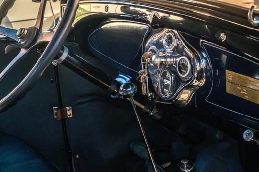 Lisbon, Portugal - Sep 29, 2024: Black interior with steering wheel, gear stick and car dashboard of vintage Ford A Tudor Sedan in selective focus. Keys in ignition switch. Ford Motor Company, USA.