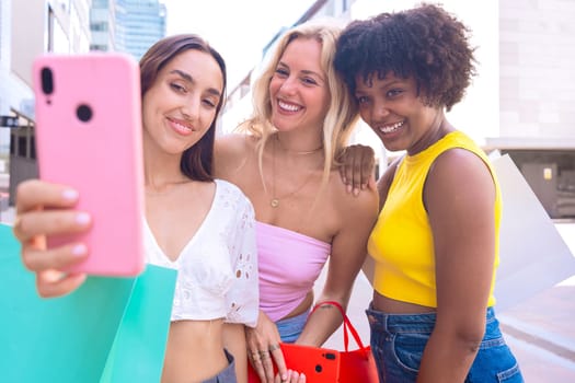 Three young women sitting outdoors, smiling, and taking a playful selfie together. Perfect for concepts like friendship, happiness, social media, and outdoor lifestyle.