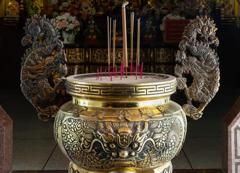 Samut Prakan, Thailand - Jan 11, 2025 - Incense smoke burning straight up on Metal dragons sculpture decorate on Golden incense burner inside the Buddhist temple of Wat Dhammakatanyu (Xian Lo Dai Tien Gong). Taiwanese art style, use it as your Wallpaper, Poster and Copy space, Selective focus.