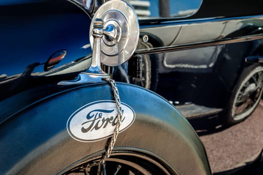 Lisbon, Portugal - Sep 29, 2024: Close view of black Ford Model T, known as Tin Lizzie, spare wheel on sunny day. Spare tyre and wheel in leather case with Ford logo printed and metallic rear mirror, Economy car, 1920s, , Ford Motor Company, USA