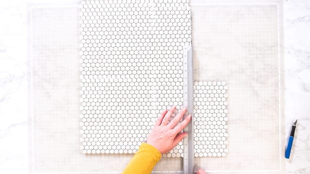 Flat lay. In the process of mounting peel and stick mosaic tiles onto a foam board, perfect for enhancing a food photography studio's aesthetic.