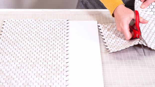 In the process of mounting peel and stick mosaic tiles onto a foam board, perfect for enhancing a food photography studio's aesthetic.