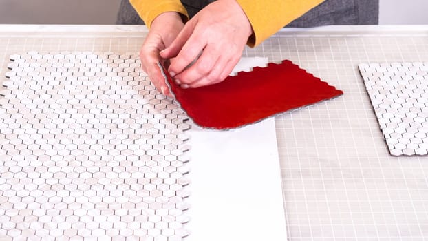 In the process of mounting peel and stick mosaic tiles onto a foam board, perfect for enhancing a food photography studio's aesthetic.
