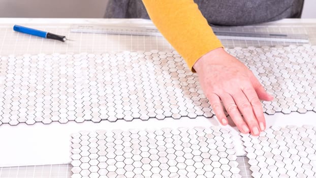 In the process of mounting peel and stick mosaic tiles onto a foam board, perfect for enhancing a food photography studio's aesthetic.