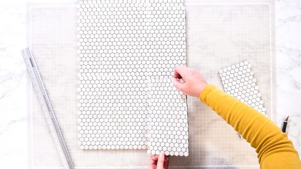Flat lay. In the process of mounting peel and stick mosaic tiles onto a foam board, perfect for enhancing a food photography studio's aesthetic.