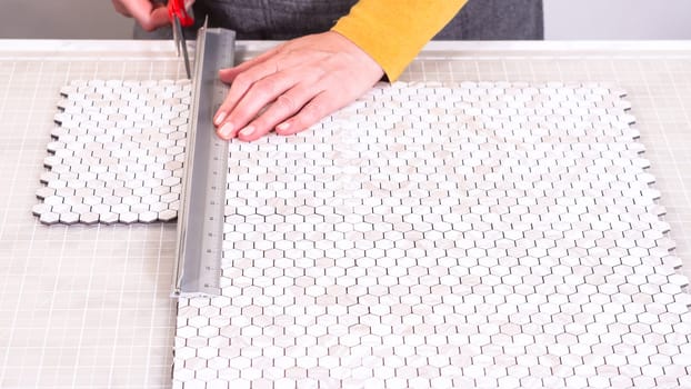 In the process of mounting peel and stick mosaic tiles onto a foam board, perfect for enhancing a food photography studio's aesthetic.