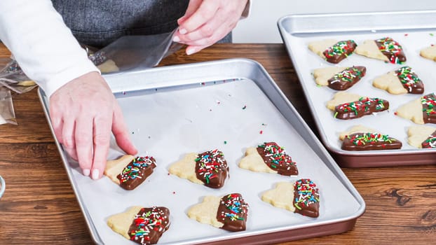 Carefully packaging Christmas cutout cookies, half-dipped in chocolate and presented in clear cellophane wrapping, perfect for festive gifting.