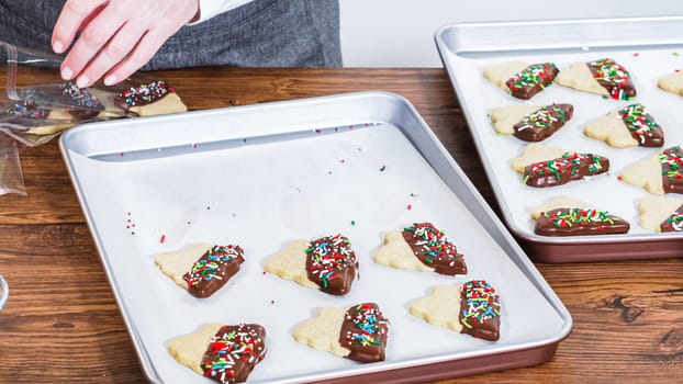 Carefully packaging Christmas cutout cookies, half-dipped in chocolate and presented in clear cellophane wrapping, perfect for festive gifting.