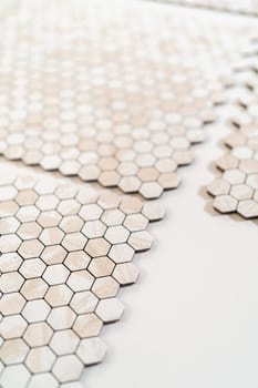 In the process of mounting peel and stick mosaic tiles onto a foam board, perfect for enhancing a food photography studio's aesthetic.