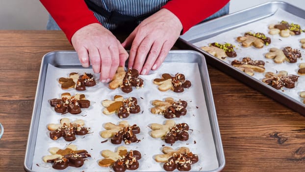 Carefully packaging Christmas cutout cookies, half-dipped in chocolate and presented in clear cellophane wrapping, perfect for festive gifting.
