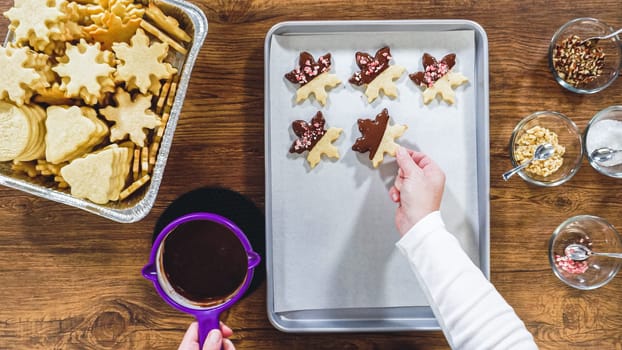 Flat lay. Creating snowflake-shaped cutout sugar cookies, dipped in chocolate, and adorned with different toppings.