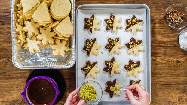 Flat lay. Creating snowflake-shaped cutout sugar cookies, dipped in chocolate, and adorned with different toppings.