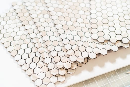 In the process of mounting peel and stick mosaic tiles onto a foam board, perfect for enhancing a food photography studio's aesthetic.