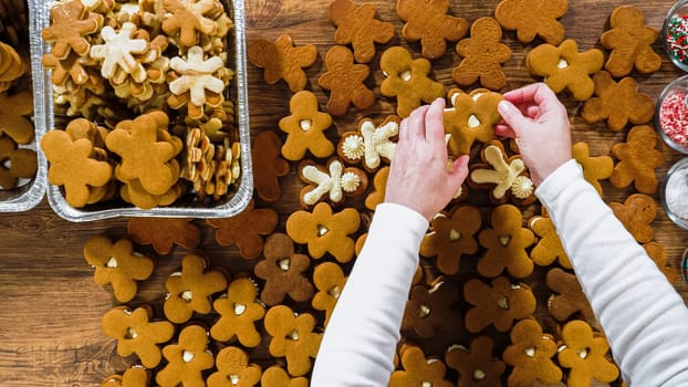 Flat lay. Crafting gingerbread cookie sandwiches with eggnog buttercream, presented on a rustic wooden table for Christmas gifting.