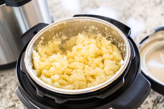 In a sleek modern kitchen, preparing velvety mashed potatoes using a pressure cooker for a quick and delicious meal.