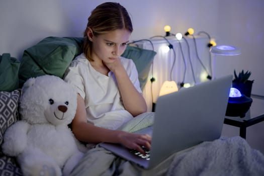 Cute Little Girl Typing On A Laptop In Bed Before Sleep, Surfing On The Internet
