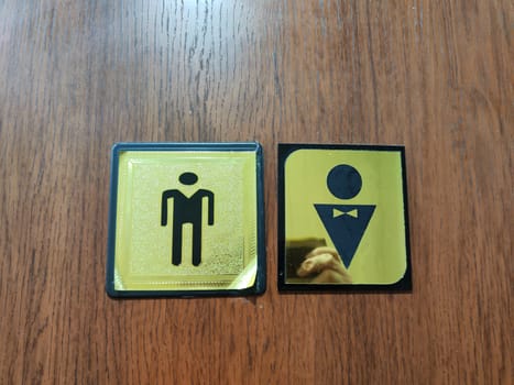 Gold and black signs display symbols for male and female restrooms in a modern indoor setting.