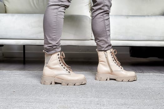 Model stands confidently in fashionable boots, highlighting a chic look in a contemporary indoor atmosphere.