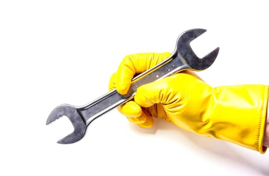 A hand wearing a bright yellow rubber glove grips a large wrench, ready for maintenance tasks in a clean setting.