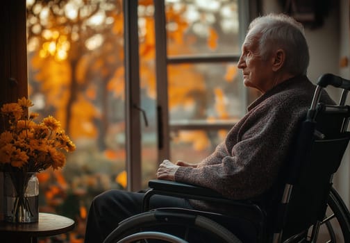 An elderly man sits in a wheelchair looking into the distance. Selective focus.