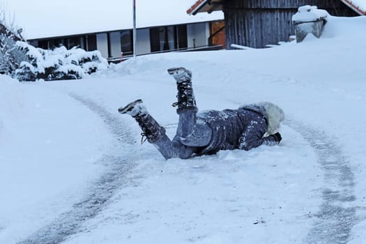 Rutschgefahr auf einer glatten Straße im Winter. Eine Frau ist auf dem Schnee ausgerutscht und hingefallen