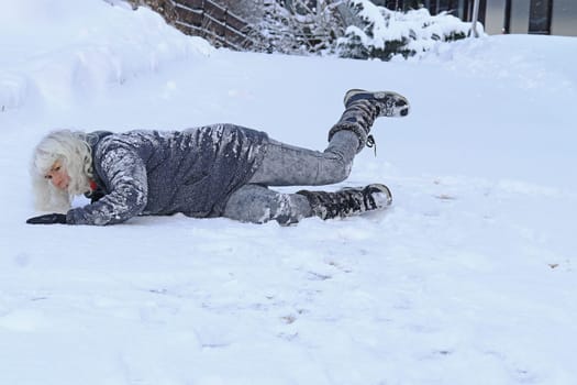 Rutschgefahr auf einer glatten Straße im Winter. Eine Frau ist auf dem Schnee ausgerutscht und hingefallen