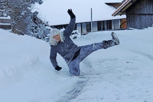 Rutschgefahr auf einer glatten Straße im Winter. Eine Frau ist auf dem Schnee ausgerutscht und hingefallen