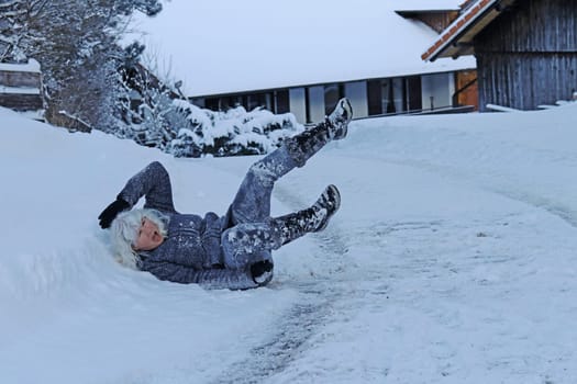 Rutschgefahr auf einer glatten Straße im Winter. Eine Frau ist auf dem Schnee ausgerutscht und hingefallen