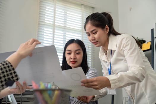 Two professionals reviewing data reports with a colleague, emphasizing teamwork and effective communication in a bright office environment.